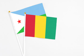 Guinea and Djibouti stick flags on white background. High quality fabric, miniature national flag. Peaceful global concept.White floor for copy space.