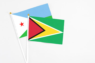 Guyana and Djibouti stick flags on white background. High quality fabric, miniature national flag. Peaceful global concept.White floor for copy space.
