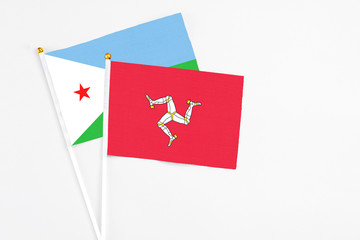 Isle Of Man and Djibouti stick flags on white background. High quality fabric, miniature national flag. Peaceful global concept.White floor for copy space.