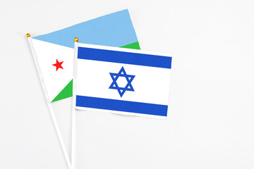 Israel and Djibouti stick flags on white background. High quality fabric, miniature national flag. Peaceful global concept.White floor for copy space.
