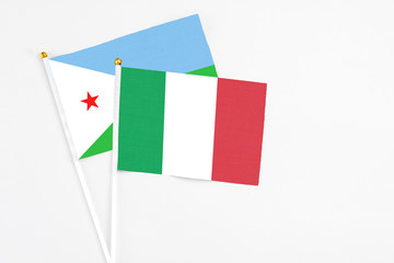 Italy and Djibouti stick flags on white background. High quality fabric, miniature national flag. Peaceful global concept.White floor for copy space.