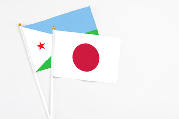 Japan and Djibouti stick flags on white background. High quality fabric, miniature national flag. Peaceful global concept.White floor for copy space.