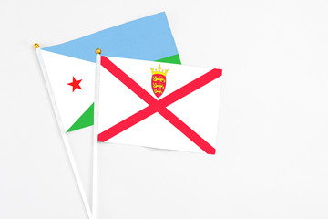 Jersey and Djibouti stick flags on white background. High quality fabric, miniature national flag. Peaceful global concept.White floor for copy space.