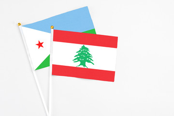 Lebanon and Djibouti stick flags on white background. High quality fabric, miniature national flag. Peaceful global concept.White floor for copy space.