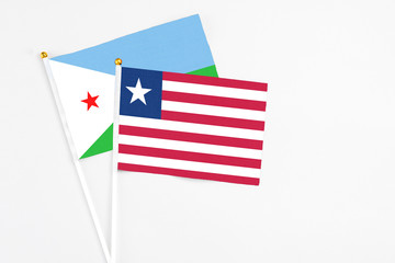 Liberia and Djibouti stick flags on white background. High quality fabric, miniature national flag. Peaceful global concept.White floor for copy space.