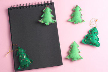 Layout for Merry Christmas to-do list. black notebook on pink background. toys made of felt in the...