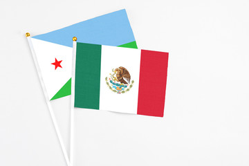 Mexico and Djibouti stick flags on white background. High quality fabric, miniature national flag. Peaceful global concept.White floor for copy space.