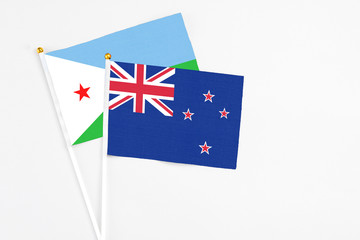 Fototapeta premium New Zealand and Djibouti stick flags on white background. High quality fabric, miniature national flag. Peaceful global concept.White floor for copy space.