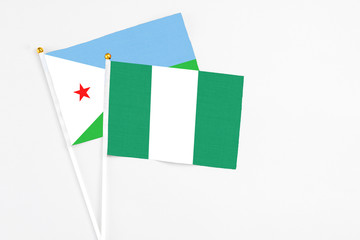 Nigeria and Djibouti stick flags on white background. High quality fabric, miniature national flag. Peaceful global concept.White floor for copy space.