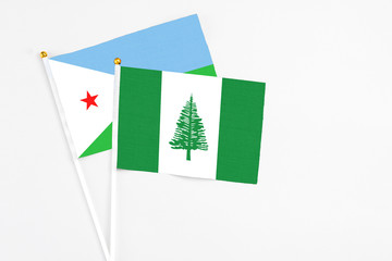Norfolk Island and Djibouti stick flags on white background. High quality fabric, miniature national flag. Peaceful global concept.White floor for copy space.