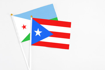 Puerto Rico and Djibouti stick flags on white background. High quality fabric, miniature national flag. Peaceful global concept.White floor for copy space.