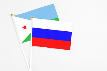 Russia and Djibouti stick flags on white background. High quality fabric, miniature national flag. Peaceful global concept.White floor for copy space.