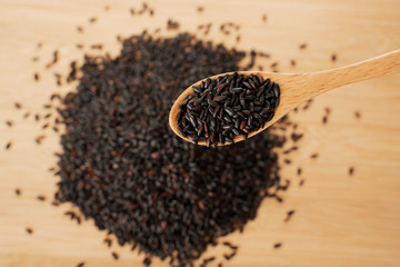 black rice pile and wooden spoon on wooden table