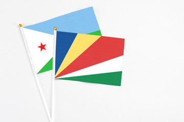 Seychelles and Djibouti stick flags on white background. High quality fabric, miniature national flag. Peaceful global concept.White floor for copy space.