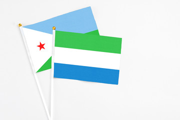 Sierra Leone and Djibouti stick flags on white background. High quality fabric, miniature national flag. Peaceful global concept.White floor for copy space.