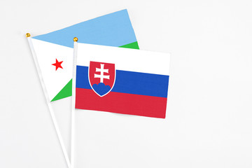 Slovakia and Djibouti stick flags on white background. High quality fabric, miniature national flag. Peaceful global concept.White floor for copy space.