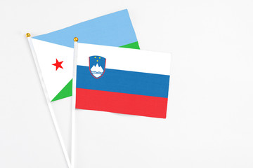 Slovenia and Djibouti stick flags on white background. High quality fabric, miniature national flag. Peaceful global concept.White floor for copy space.