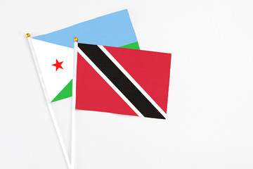 Trinidad And Tobago and Djibouti stick flags on white background. High quality fabric, miniature national flag. Peaceful global concept.White floor for copy space.