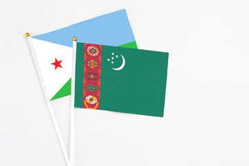 Turkmenistan and Djibouti stick flags on white background. High quality fabric, miniature national flag. Peaceful global concept.White floor for copy space.