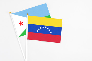 Venezuela and Djibouti stick flags on white background. High quality fabric, miniature national flag. Peaceful global concept.White floor for copy space.