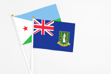 Fototapeta premium British Virgin Islands and Djibouti stick flags on white background. High quality fabric, miniature national flag. Peaceful global concept.White floor for copy space.