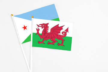 Wales and Djibouti stick flags on white background. High quality fabric, miniature national flag. Peaceful global concept.White floor for copy space.