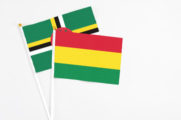 Bolivia and Dominica stick flags on white background. High quality fabric, miniature national flag. Peaceful global concept.White floor for copy space.