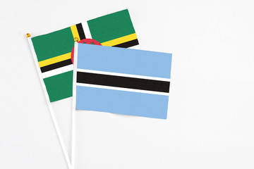 Botswana and Dominica stick flags on white background. High quality fabric, miniature national flag. Peaceful global concept.White floor for copy space.