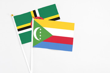 Comoros and Dominica stick flags on white background. High quality fabric, miniature national flag. Peaceful global concept.White floor for copy space.