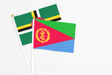 Eritrea and Dominica stick flags on white background. High quality fabric, miniature national flag. Peaceful global concept.White floor for copy space.