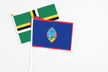 Guam and Dominica stick flags on white background. High quality fabric, miniature national flag. Peaceful global concept.White floor for copy space.