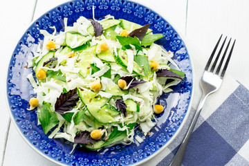 Green salad with sprouted chickpeas in a blue plate on a light background. Vegetarian raw food.