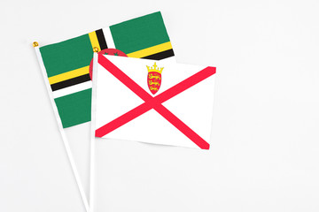 Jersey and Dominica stick flags on white background. High quality fabric, miniature national flag. Peaceful global concept.White floor for copy space.
