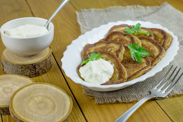 Pancakes of rye flour with sour cream on a wooden table. Tasty and healthy Breakfast.