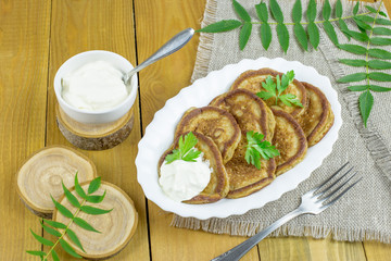 Pancakes of rye flour with sour cream on a wooden table. Tasty and healthy Breakfast.