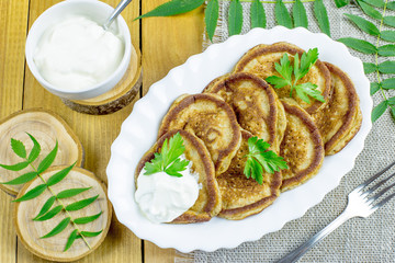 Pancakes of rye flour with sour cream on a wooden table. Tasty and healthy Breakfast.