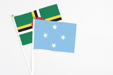 Micronesia and Dominica stick flags on white background. High quality fabric, miniature national flag. Peaceful global concept.White floor for copy space.