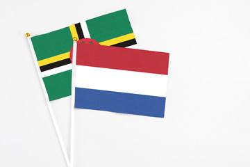 Netherlands and Dominica stick flags on white background. High quality fabric, miniature national flag. Peaceful global concept.White floor for copy space.