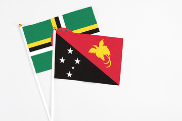 Papua New Guinea and Dominica stick flags on white background. High quality fabric, miniature national flag. Peaceful global concept.White floor for copy space.