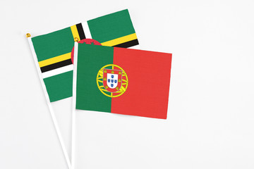 Portugal and Dominica stick flags on white background. High quality fabric, miniature national flag. Peaceful global concept.White floor for copy space.