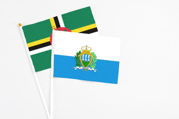 San Marino and Dominica stick flags on white background. High quality fabric, miniature national flag. Peaceful global concept.White floor for copy space.