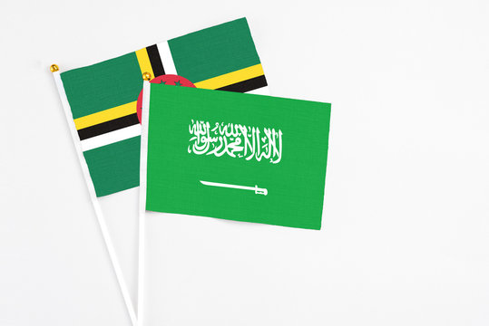 Saudi Arabia and Dominica stick flags on white background. High quality fabric, miniature national flag. Peaceful global concept.White floor for copy space.