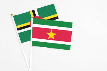 Suriname and Dominica stick flags on white background. High quality fabric, miniature national flag. Peaceful global concept.White floor for copy space.