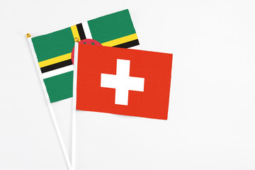 Switzerland and Dominica stick flags on white background. High quality fabric, miniature national flag. Peaceful global concept.White floor for copy space.