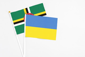 Ukraine and Dominica stick flags on white background. High quality fabric, miniature national flag....