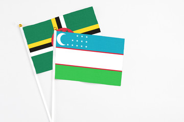 Uzbekistan and Dominica stick flags on white background. High quality fabric, miniature national flag. Peaceful global concept.White floor for copy space.