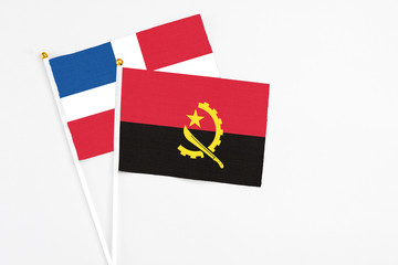 Angola and Dominican Republic stick flags on white background. High quality fabric, miniature national flag. Peaceful global concept.White floor for copy space.