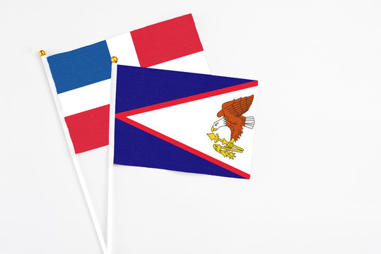 American Samoa and Dominican Republic stick flags on white background. High quality fabric, miniature national flag. Peaceful global concept.White floor for copy space.