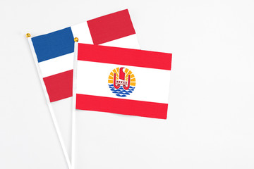 French Polynesia and Dominican Republic stick flags on white background. High quality fabric, miniature national flag. Peaceful global concept.White floor for copy space.