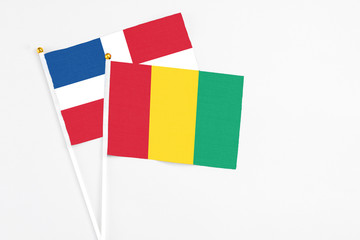 Guinea and Dominican Republic stick flags on white background. High quality fabric, miniature national flag. Peaceful global concept.White floor for copy space.